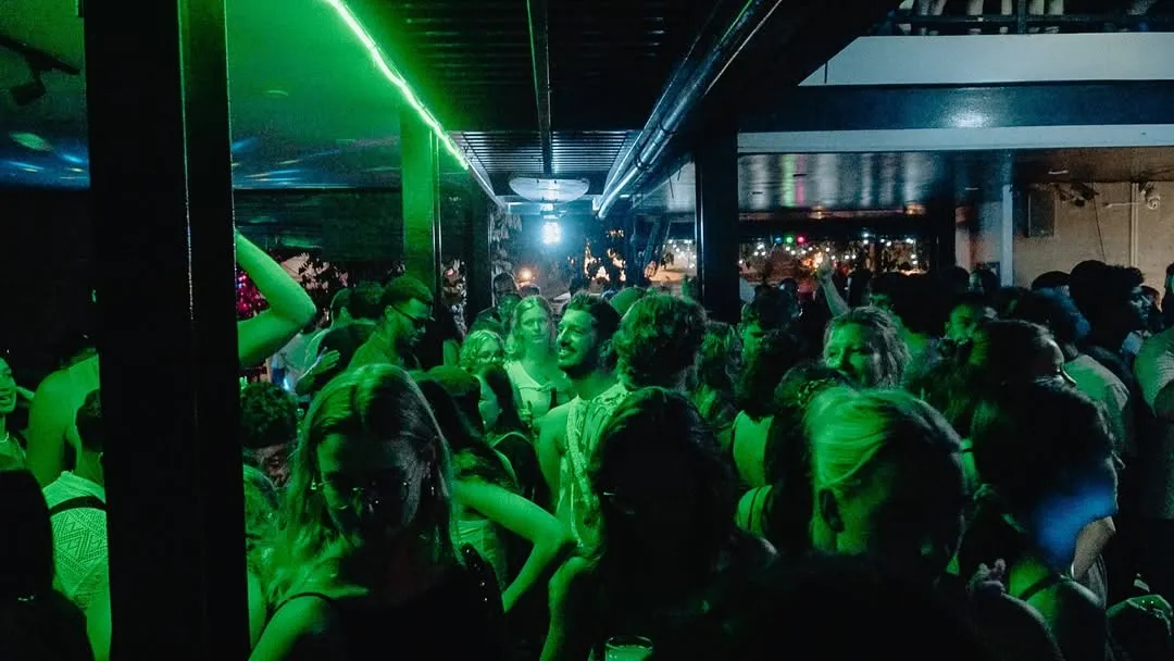Guests dancing under green neon at a night party at Siargao Bed & Brewery
