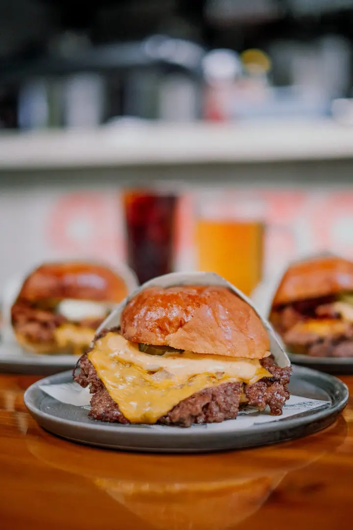 Smash burger with melted cheese and pickles, the bar behind it