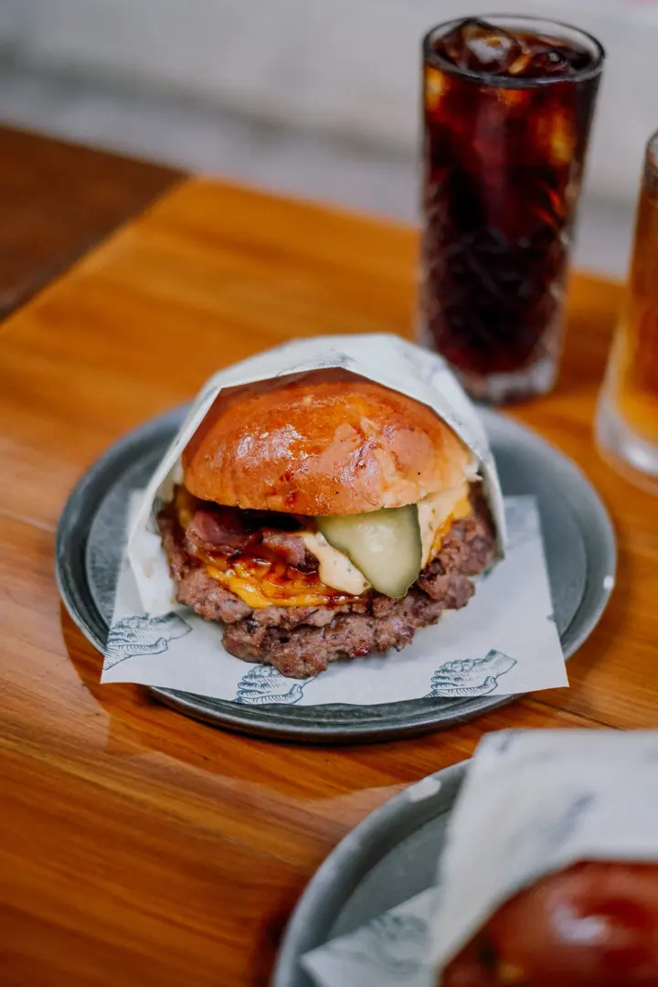 Close view of a smash burger with melted cheese and pickles on a brioche bun