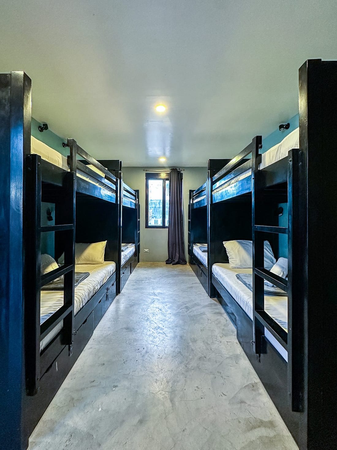 Dorm room at Siargao Bed & Brewery with black bunk beds, reading lamps and fresh linens