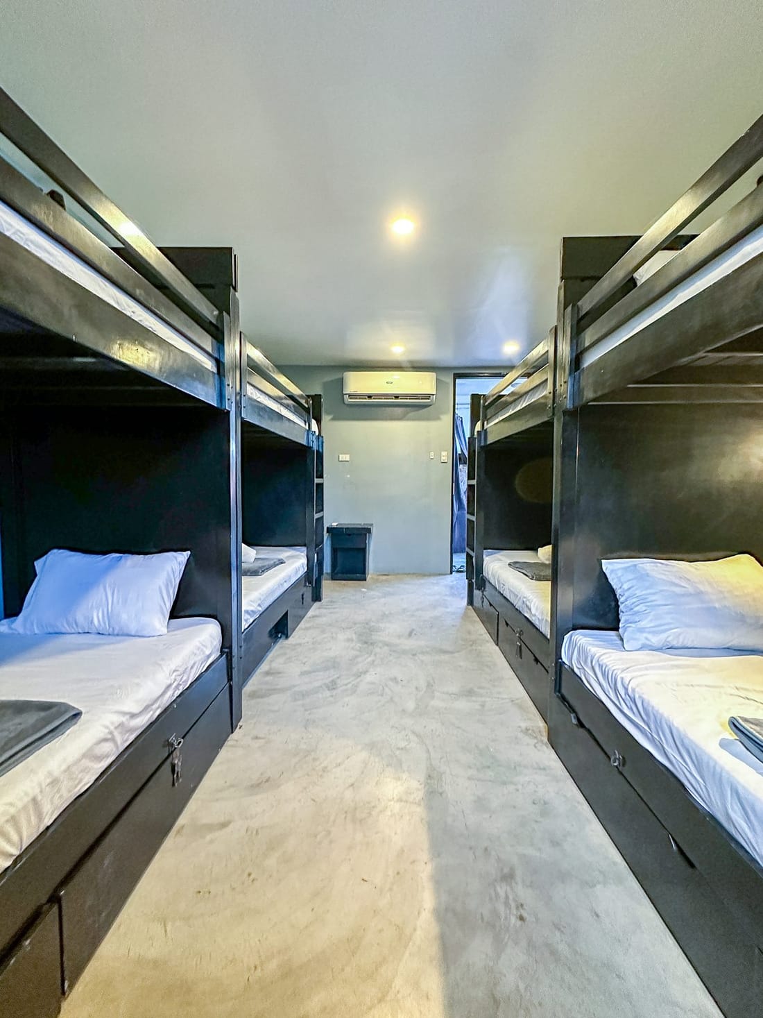 Dorm bunk with a curtain, folded towels and a wall air conditioner