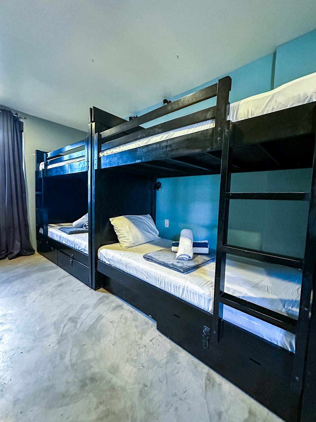 Black bunk bed in the dorm, with a reading lamp, folded towels and a ladder