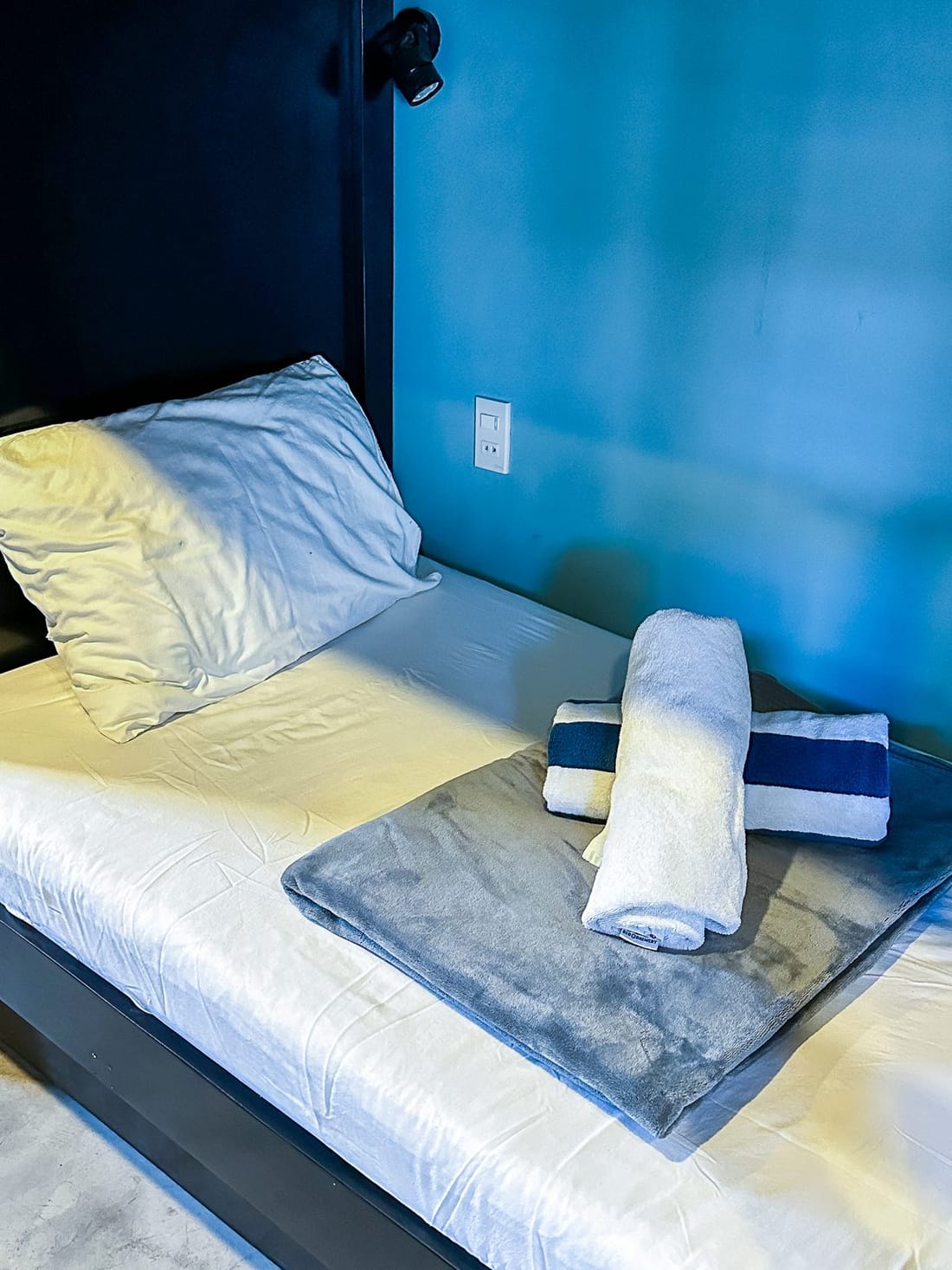 Dorm aisle with black bunk beds, drawers under the bunks and a curtain at the end of the room